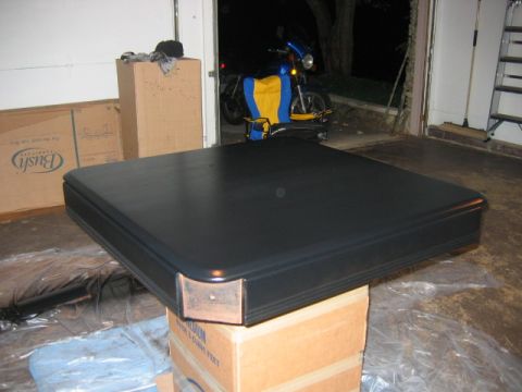 1985 Ford LTD Crown Victoria - A black table with copper corner accents is placed on boxes in a garage, with a motorcycle visible in the background.