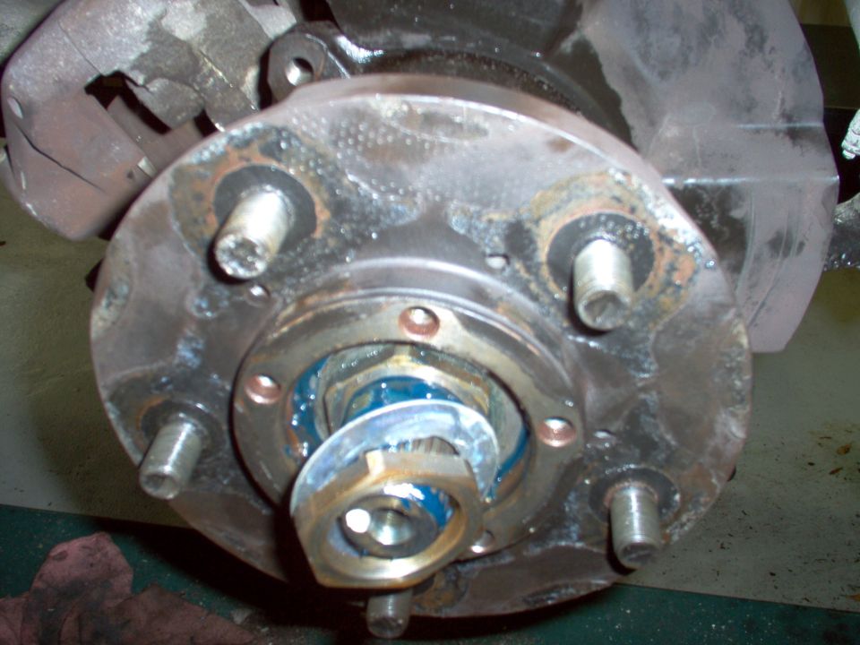 Install the thick washer and set the inner nut by hand while rotating the hub.  Then install the lock ring & the outer nut.

The rotor should have been on the hub already.  I had to backtrack later.