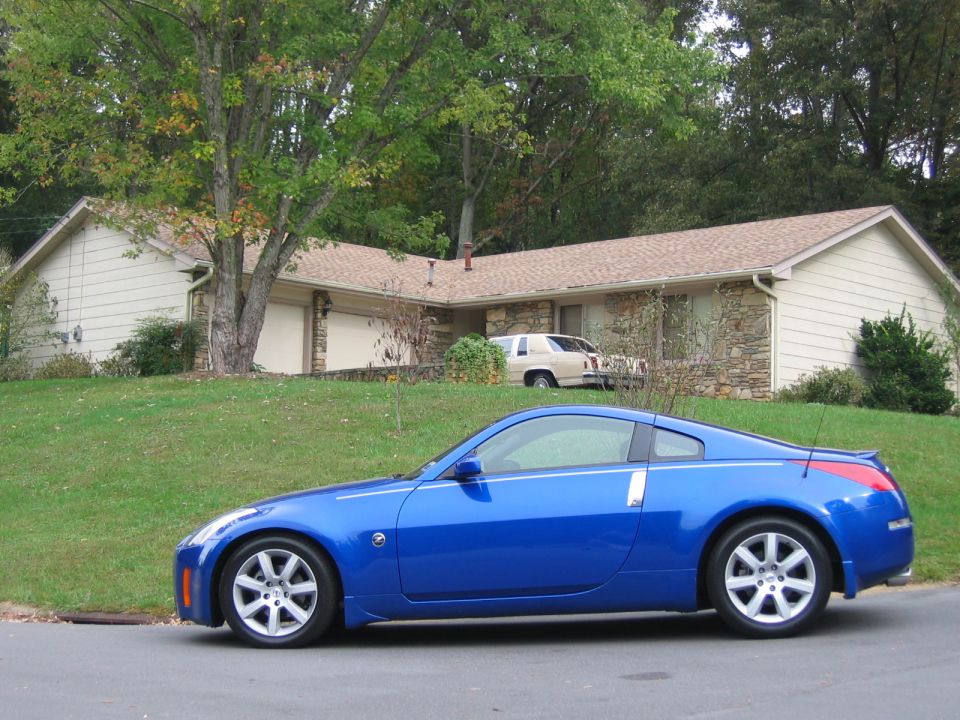 Blue coupe parked on street, beige sedan in driveway behind it