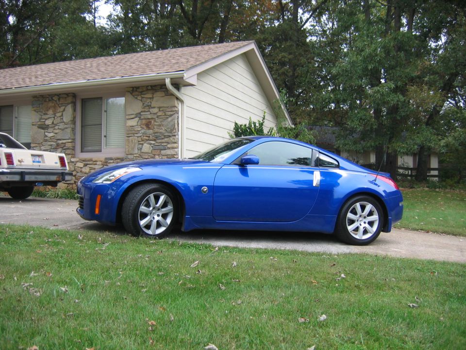 Blue coupe parked next to an older beige car in front of a house