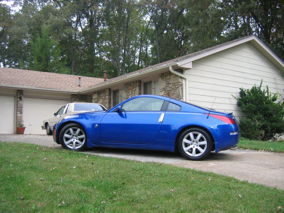 Blue coupe parked on driveway, tan sedan in background
