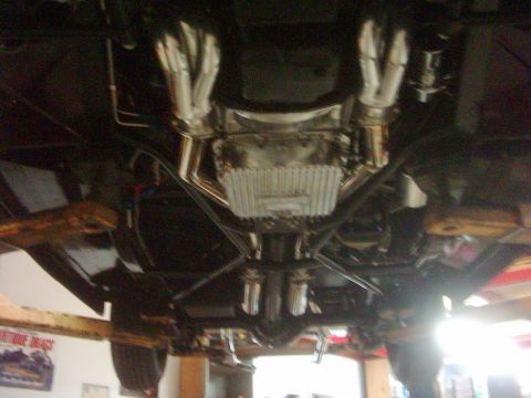 1978 Ford Bronco - The underside of a vehicle shows custom exhaust headers and a large transmission pan.
