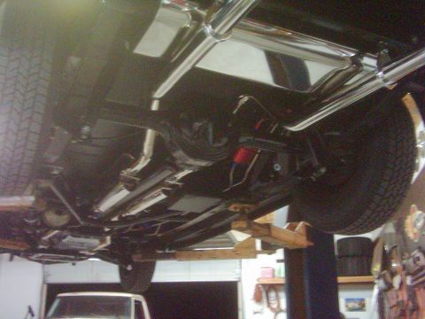 1978 Ford Bronco - A detailed look at the underside of a vehicle, highlighting its exhaust system and suspension, as it is raised on a lift.