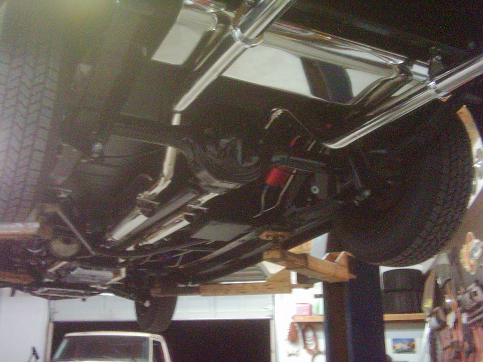 Undercarriage view of a vehicle with custom exhaust and suspension components