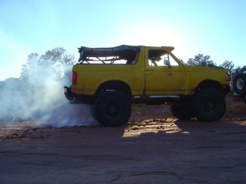 1993 Ford Bronco - A yellow 1993 Ford Bronco is seen from the side, kicking up dust with its tires.