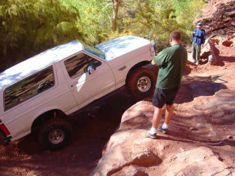 1993 Ford Bronco - White 1993 Ford Bronco tackles a challenging Moab trail with onlookers.