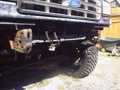 1988 Ford Bronco - Close-up of the front suspension and wheel of a Ford truck, with the bumper removed.