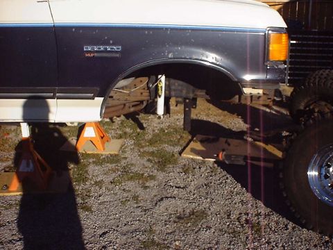 1988 Ford Bronco - The front suspension of a 1988 Ford Bronco is shown removed, with the vehicle supported by jack stands.