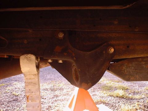1988 Ford Bronco - This photo shows the underside of a vehicle, focusing on suspension components and the frame, supported by jack stands.