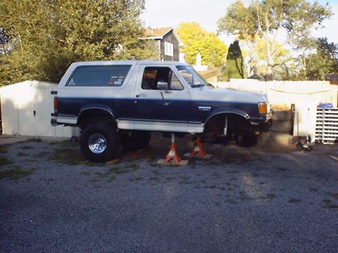 1988 Ford Bronco - This lifted Ford Bronco is on jack stands, possibly for maintenance or modification, with its front end elevated.