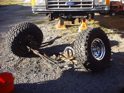 1988 Ford Bronco - Front suspension and tires removed from a 1988 Ford Bronco, with the vehicle supported by jack stands.