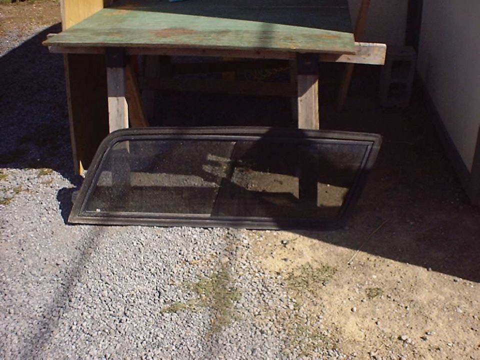 Car window frame and glass lying on gravel near a wooden structure
