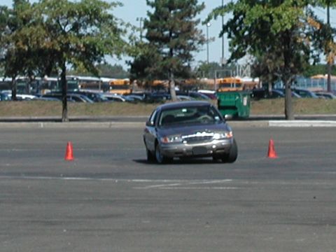 2001 Mercury Grand Marquis - A gray 2001 Mercury Grand Marquis navigates a course marked by traffic cones in a large parking lot.