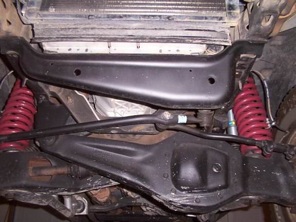 Underside front suspension view with red coil springs, black crossmember and sway bar