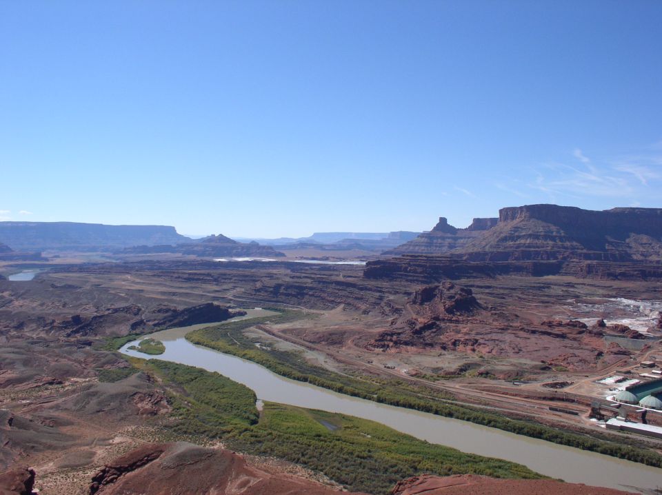 Wide view of a river winding through a desert canyon with mesas in the distance