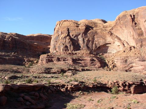 1993 Ford Bronco - A vast desert landscape with towering red rock formations and sparse vegetation under a bright blue sky.