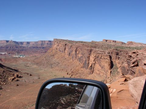 1993 Ford Bronco - A view of a vast desert canyon landscape with a side mirror reflecting off-road vehicles.