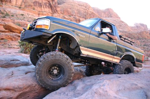 1993 Ford Bronco - This lifted 1993 Ford Bronco navigates a rocky trail in a desert landscape.