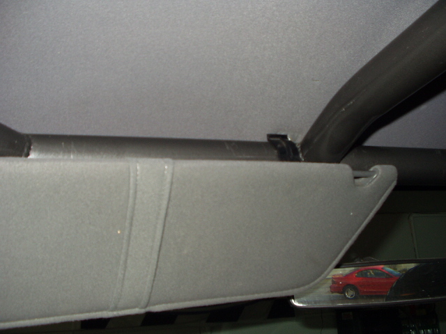 Gray sun visor and headliner interior with rearview mirror reflecting a red car
