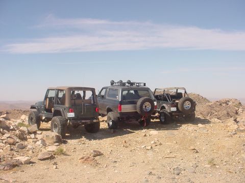 1988 Ford Bronco - Three off-road vehicles, including a 1988 Ford Bronco, are parked on a rocky hillside.