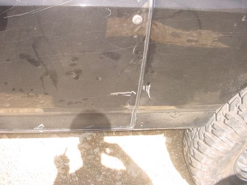 1988 Ford Bronco - Close-up of a vehicle's side panel and tire, showing wear and tear.