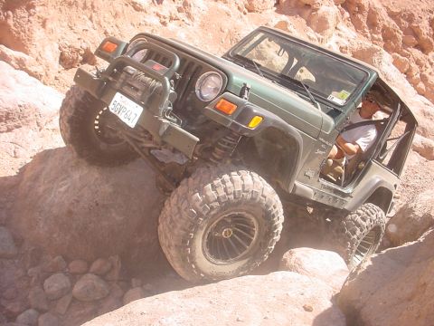 1988 Ford Bronco - Jeep Wrangler TJ navigating a rocky off-road course. The vehicle is tilted significantly.