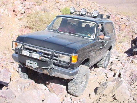 1988 Ford Bronco - Black Ford Bronco navigating a rocky trail, likely from the late 1980s or early 1990s.