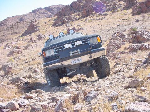 1988 Ford Bronco - This modified SUV navigates a steep, rocky incline in a desert landscape.
