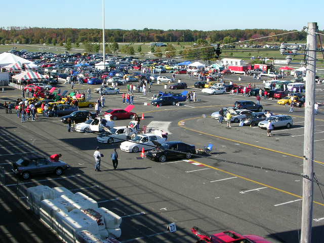 Cars parked in an outdoor lot with tents and people
