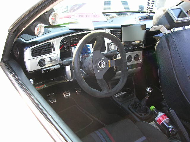 Interior view with aftermarket steering wheel, gauges, and screens