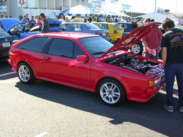 Red coupe with hood open, showing engine