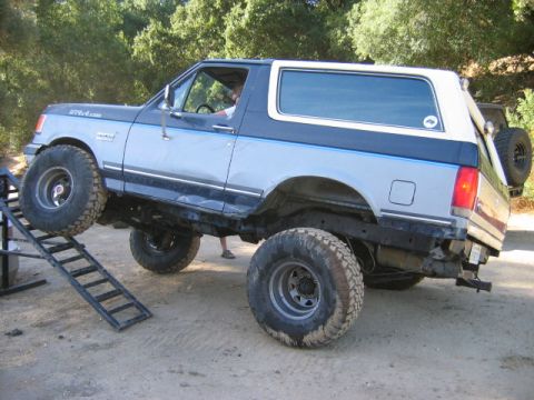1985 Ford Bronco - A lifted Ford Bronco is shown navigating an obstacle course with a ramp.