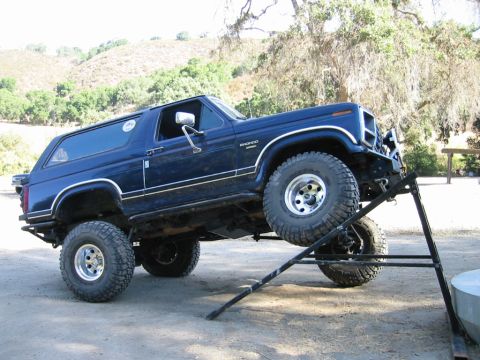 1985 Ford Bronco - A blue Ford Bronco is positioned on a ramp, with its front wheel raised off the ground.