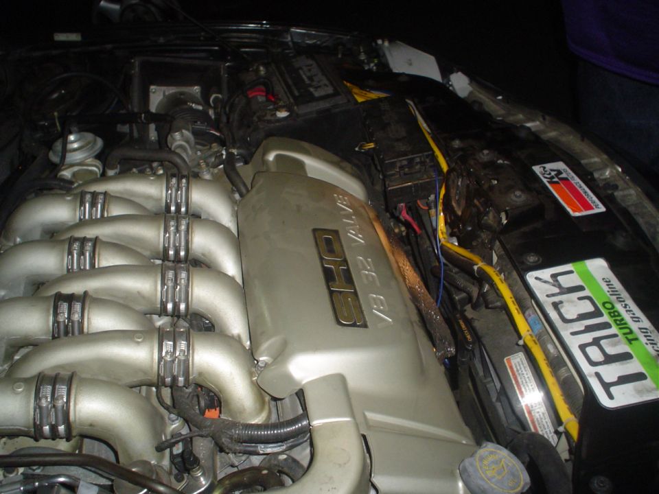 Engine bay with V6 32 valve SHO engine cover and intake runners. K&N sticker and a "TRICK TURBO racing gasoline" sticker are visible