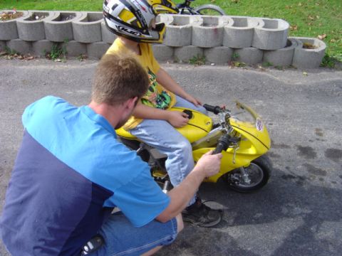 1998 Ford Taurus - An adult helps a child get ready to ride a yellow pocket bike.