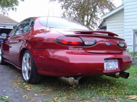 1998 Ford Taurus - Rear view of a red 1998 Ford Taurus SE sedan, showing its spoiler and dual exhaust.