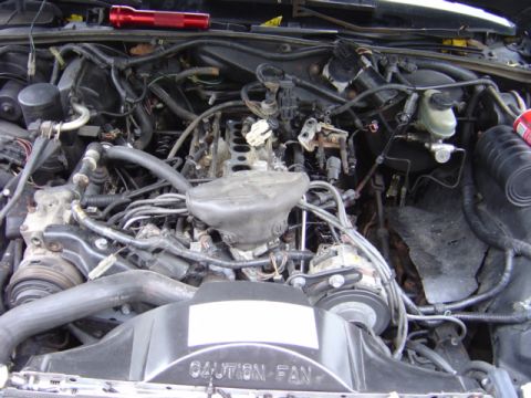1998 Ford Taurus - Close-up view of a car's engine compartment, showing various mechanical components and wiring.