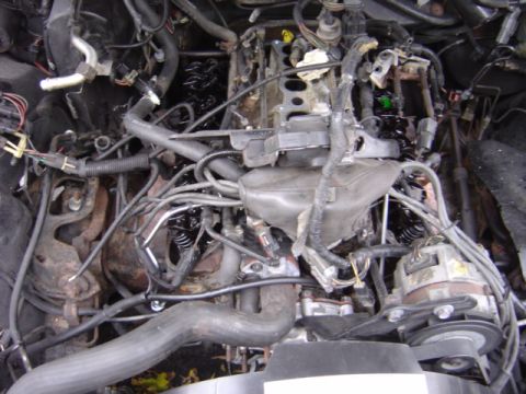 1998 Ford Taurus - A cluttered engine bay with many hoses and wires visible.