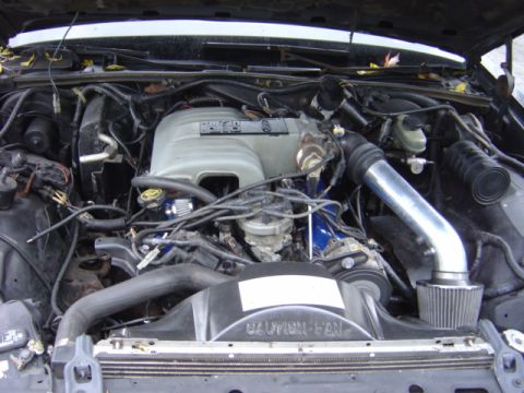 1998 Ford Taurus - The engine bay of a vehicle, showing various components and a prominent silver intake system.