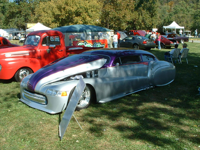 Silver and purple custom hot rod with hood open, parked on grass at a car show