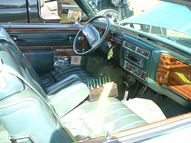 Interior of a car with green leather seats, wood trim, and a dashboard with a radio