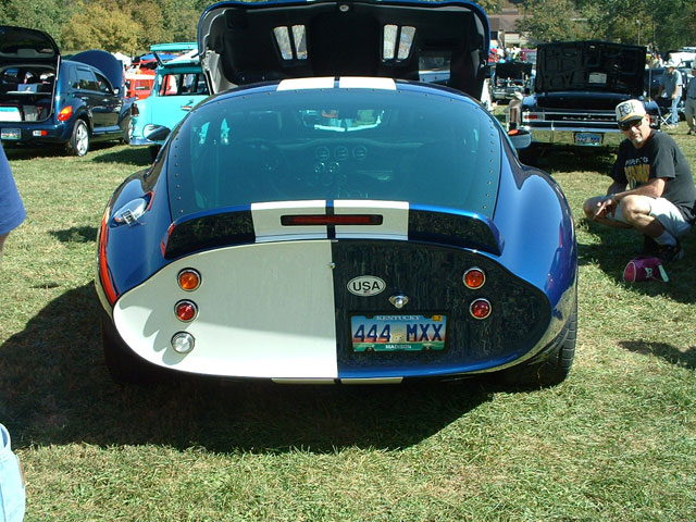 Rear view of a blue and white Shelby Cobra replica with a custom license plate