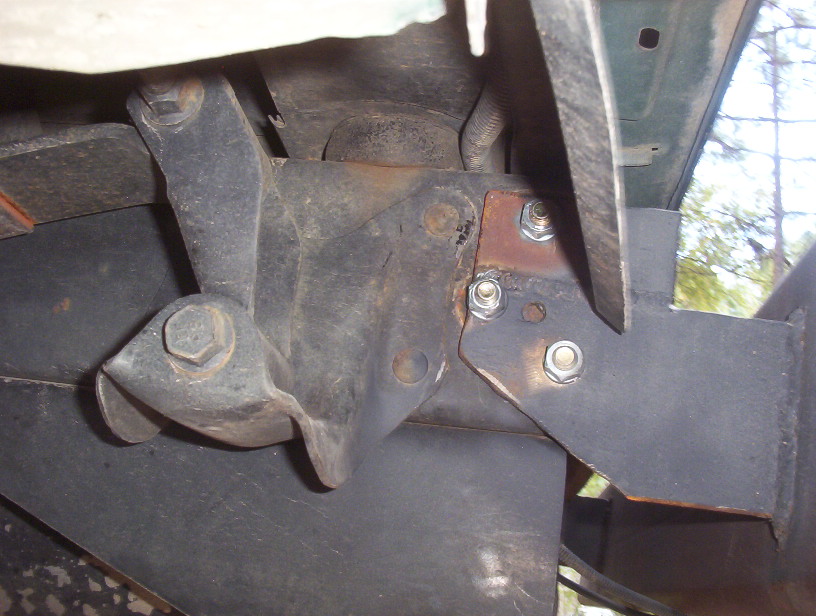 Close-up of rusted metal bracket with bolts, likely part of a vehicle's undercarriage
