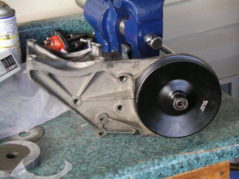 1996 Ford Bronco - Power steering pump assembly clamped in a vise, ready for work. Part number visible on the pulley.