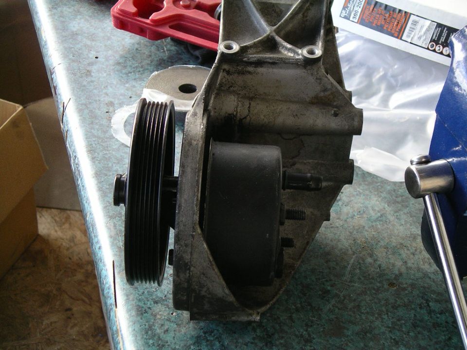 Cast metal accessory bracket with serpentine pulley on a workbench