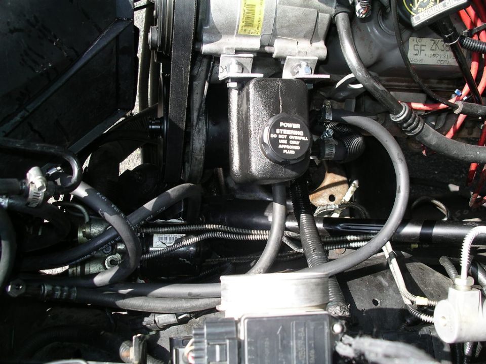 Engine bay power steering reservoir with hoses and pulley in a Ford Bronco