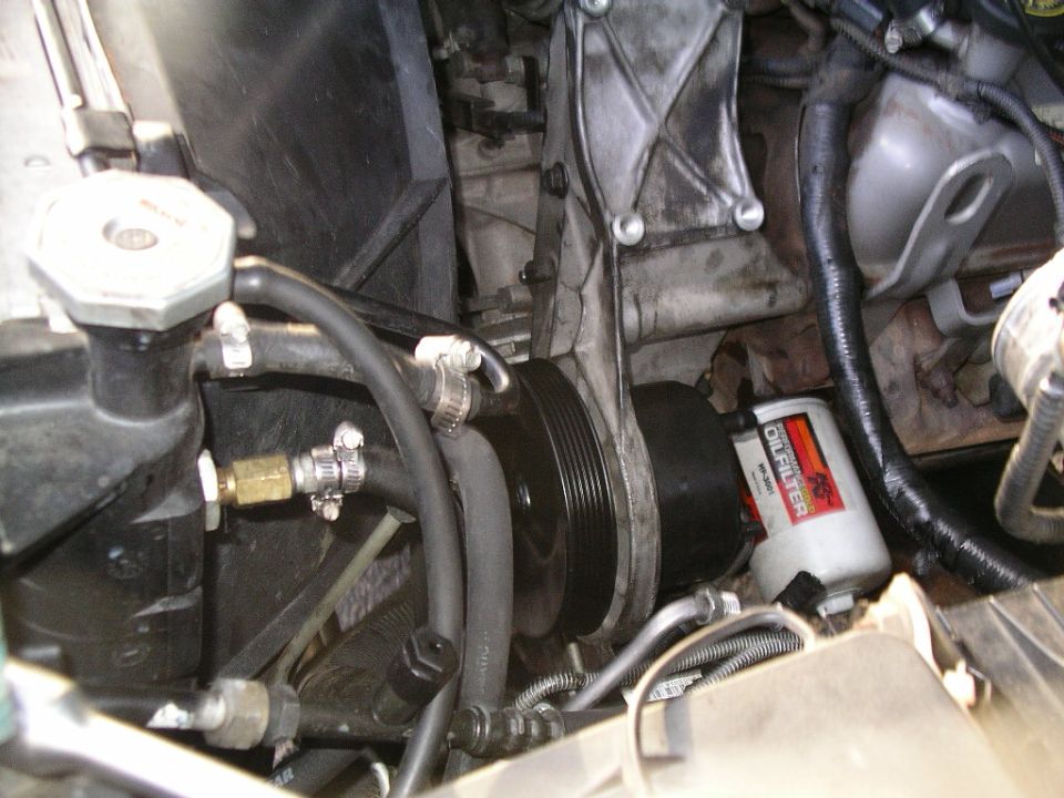 Engine bay showing pump with ribbed pulley, bracket, and red K&N oil filter