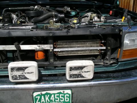 1996 Ford Bronco - The front of a green Ford truck is shown with the hood open, revealing the engine and radiator assembly.