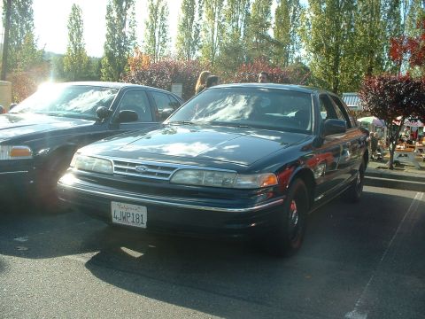 1999 Ford Crown Victoria - A dark blue Ford Crown Victoria is parked outdoors, with another vehicle partially visible to its left.