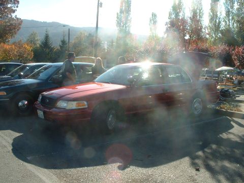 1999 Ford Crown Victoria - A red Ford Crown Victoria sedan is parked at an outdoor gathering with other vehicles present.